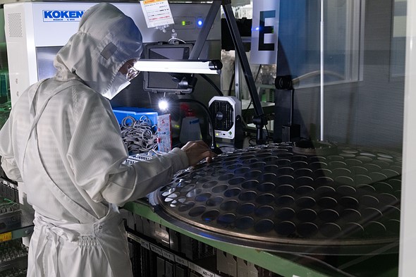 a technician loading lens elements into a tool designed to apply lens coatings a the sigma lens factory