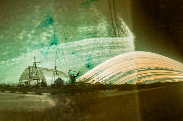 the rounded metal shield over chornobyl looms in the distance with streaks of light next to it