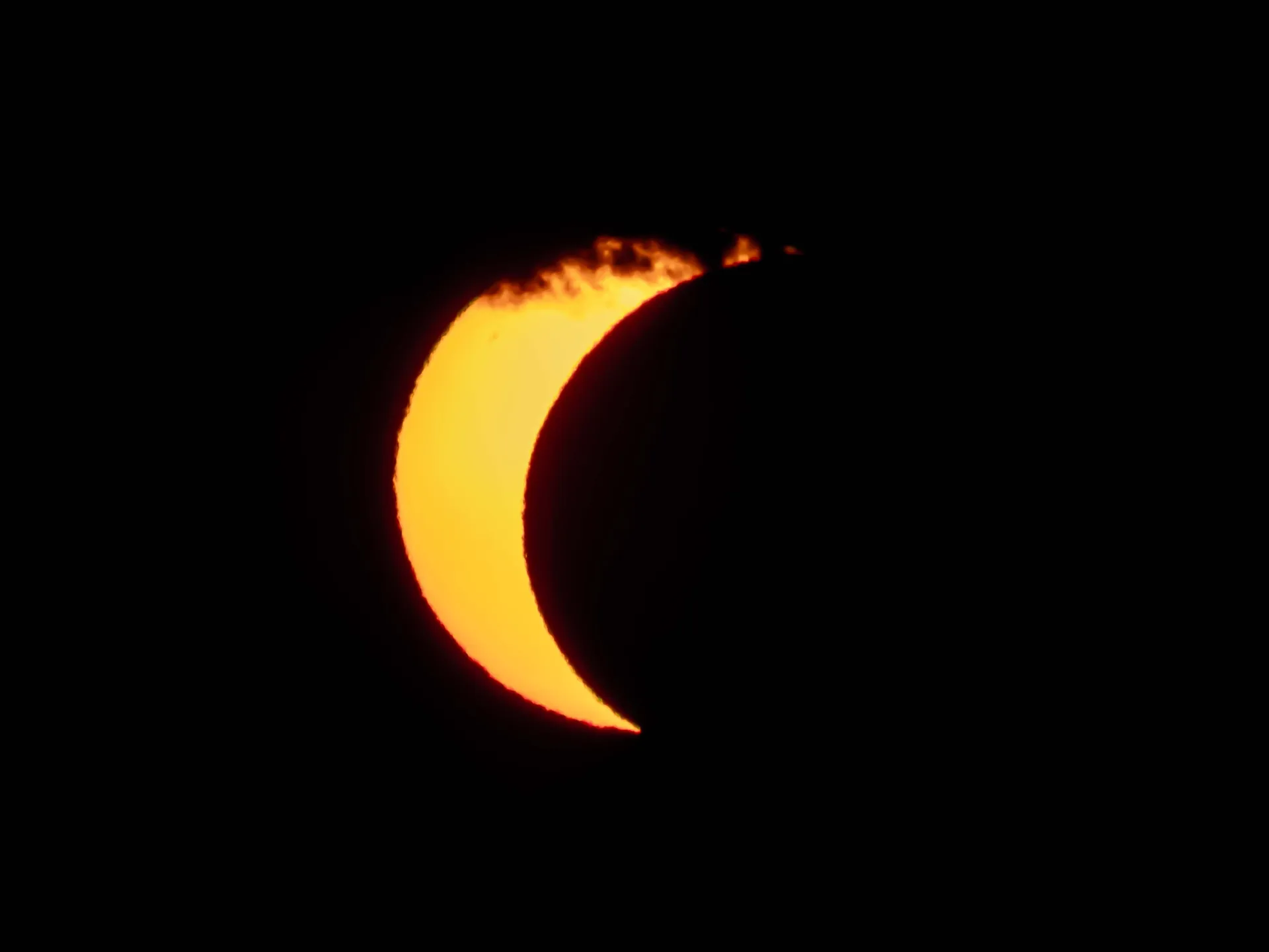 The sun's orange disk is obscured by the moon in the August 12th solar eclipse.