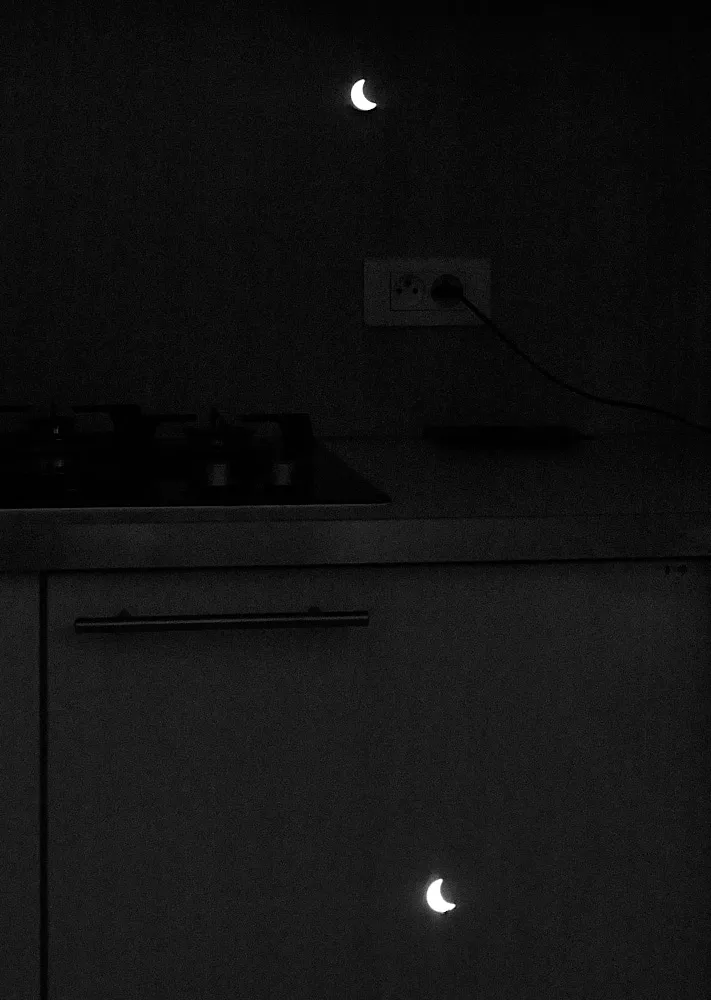 The light from a partial eclipse projects two tiny semi-circles of light into a kitchen.