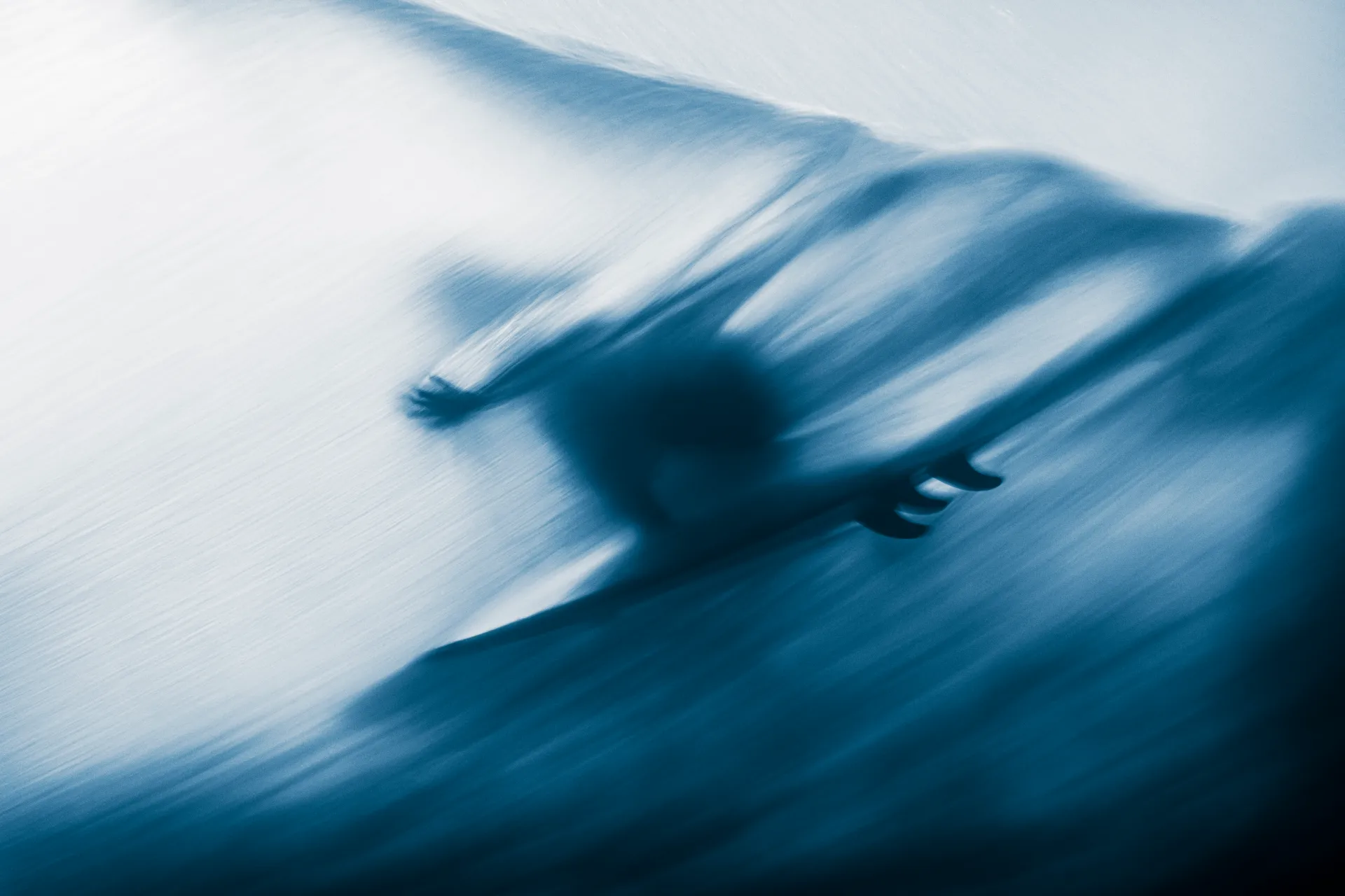 Blurred abstract scene in blue tones featuring a surfer on a wave, with fluid motion emphasizing dynamic movement.