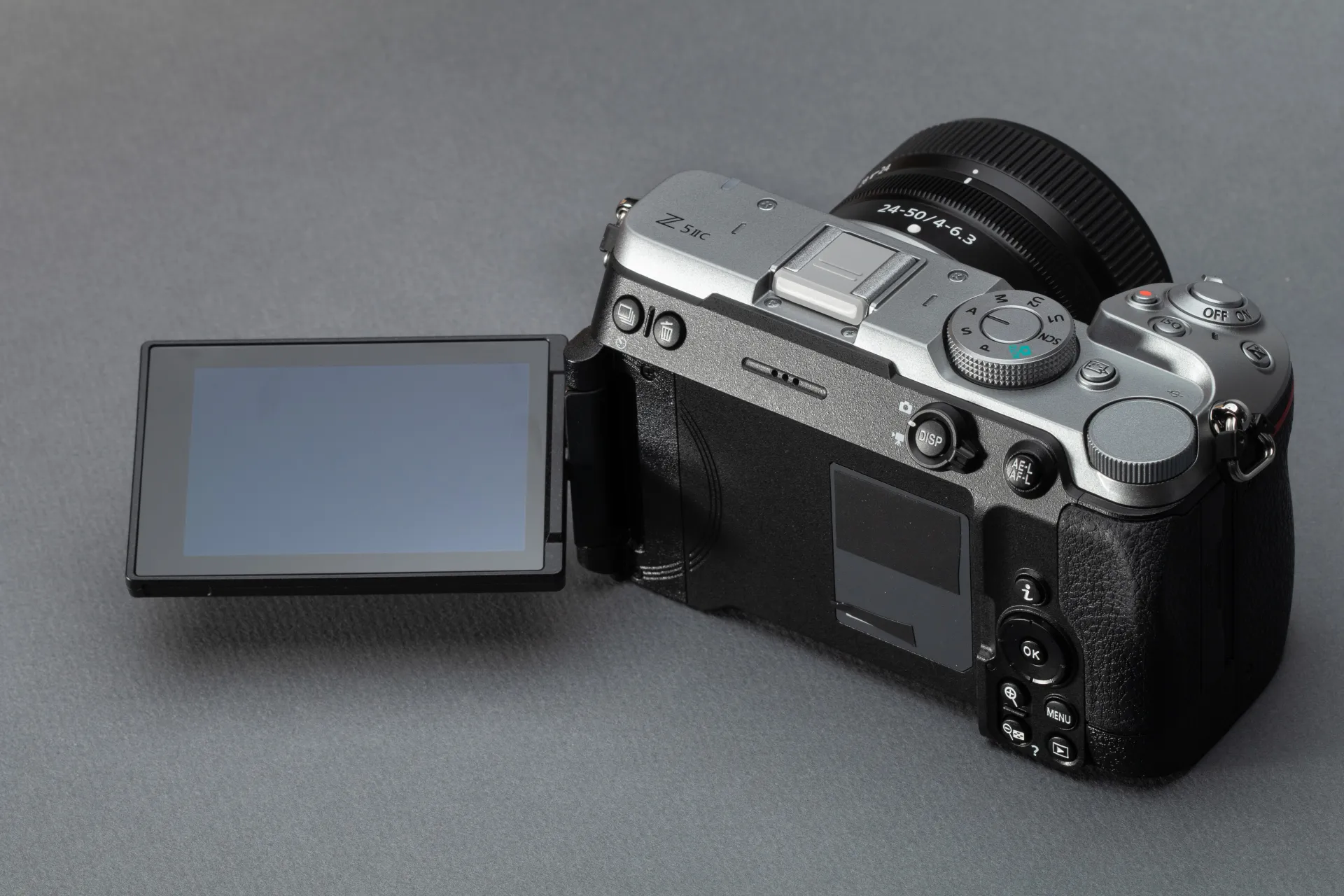 A silver Nikon Z5IIC on a gray background, with its articulating display flipped out.