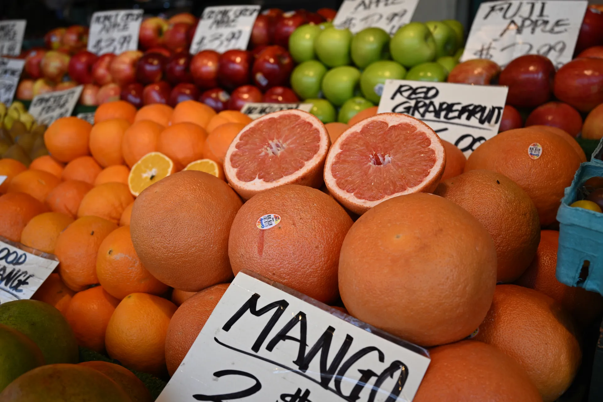 Un étal de fruits avec une pile de pamplemousses. Sur le dessus se trouve un seul
