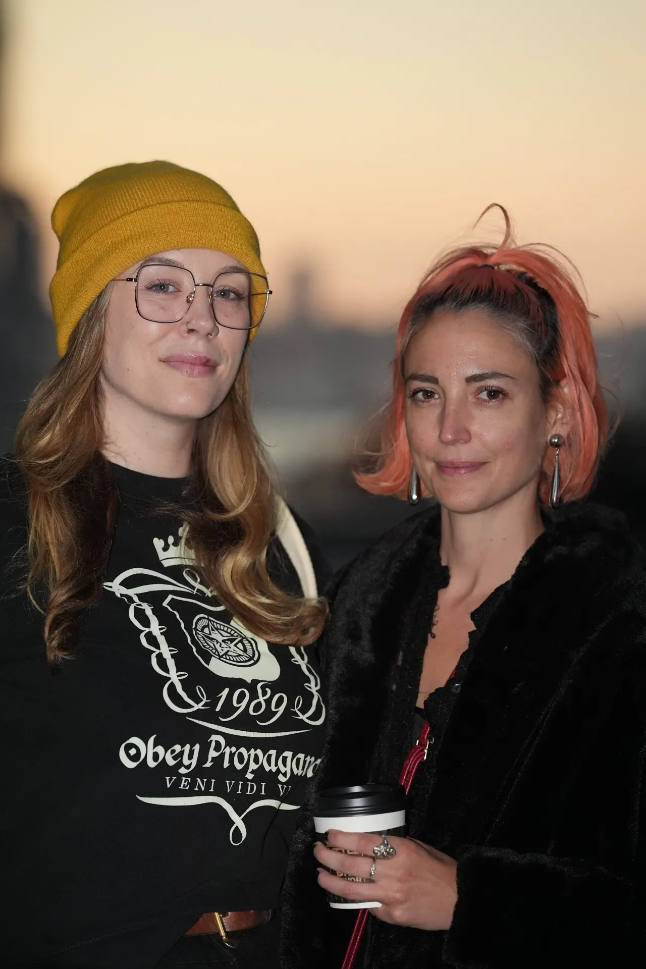 Two people stand in front of a sunset sky, their faces clearly illuminated by a flash.