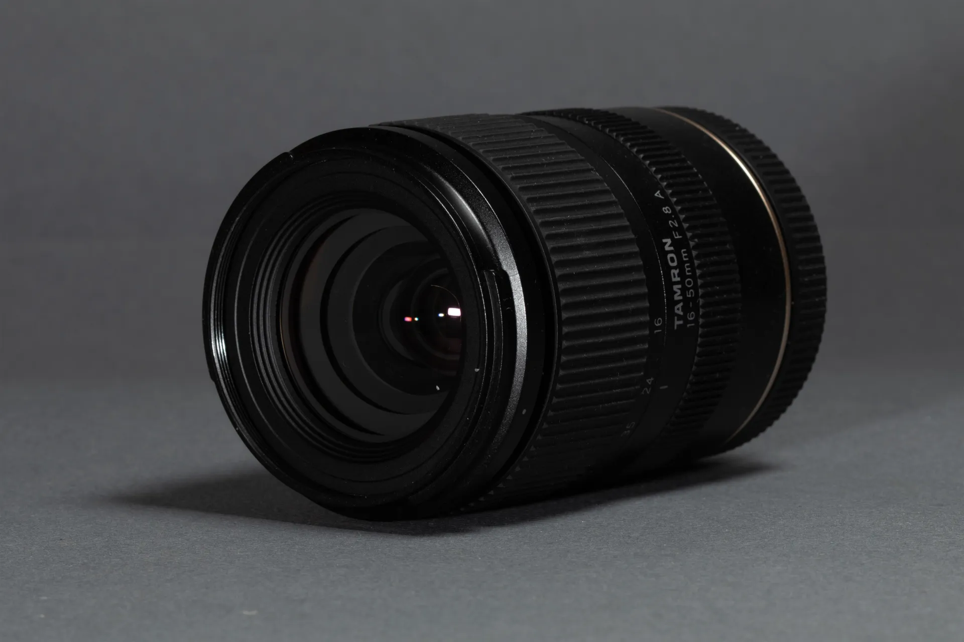 Black Tamron 16-50mm camera lens on a gray surface.